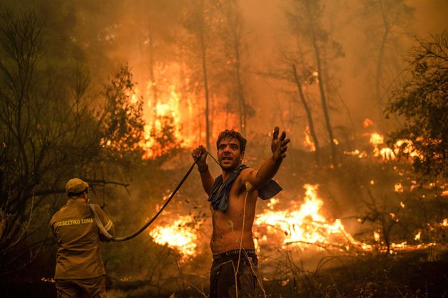 A local resident holds an empty water hose during an attempt to extinguish forest fires on Evia island in Greece.