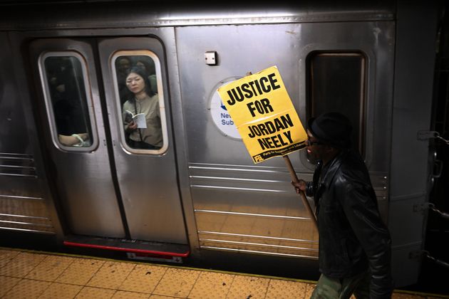A demonstrator carries a protest sign at a New York subway station during a vigil and rally on Monday, May 8.