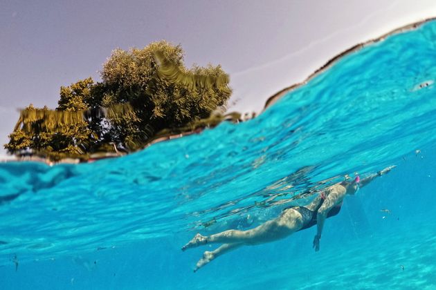 People take an early-morning swim in the Jesus Green pool on Monday as temperatures begin to rise in Cambridge, England.