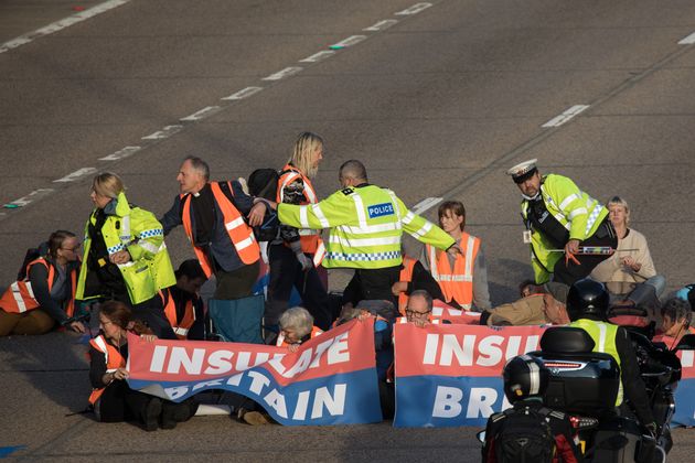 <strong>Surrey Police officers try to remove Insulate Britain climate activists from the carriageway.</strong>