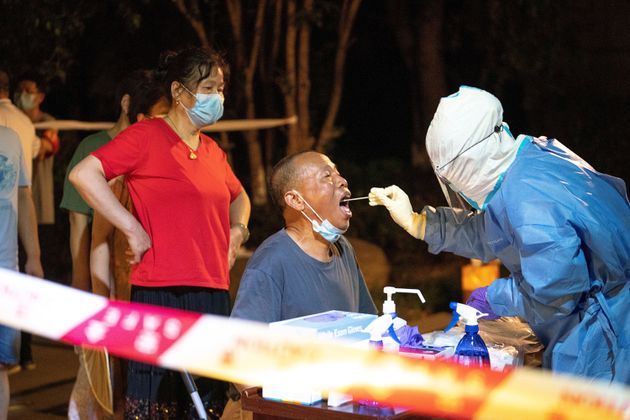 A medical worker takes a swab sample from a resident for COVID-19 nucleic acid testing in Wuhan, central China's Hubei Province, Aug. 3, 2021