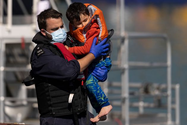 A young migrant being carried by a Border Force official after arriving into Dover on Wednesday