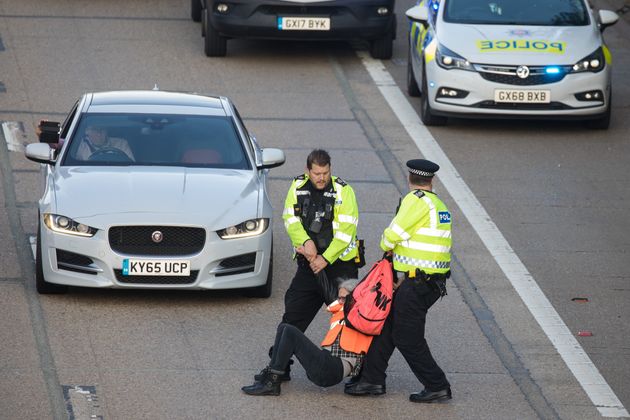 <strong>Surrey Police officers haul an Insulate Britain climate activist from the carriageway of the M25.</strong>