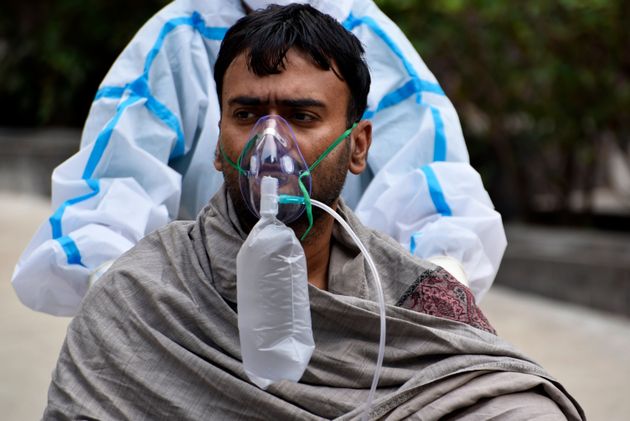 A Covid-19 patient can be seen assisted by a health worker wearing a PPE Kit inside a government hospital in Kolkata, India.