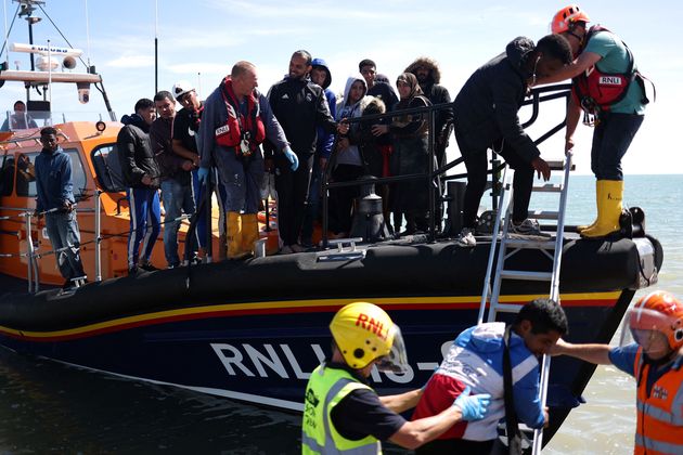 Members of Royal National Lifeboat Institution help migrants to disembark from a lifeboat on the beach at Dungeness after being picked up at sea while crossing the English Channel from France. (Photo by HENRY NICHOLLS / AFP) (Photo by HENRY NICHOLLS/AFP via Getty Images)