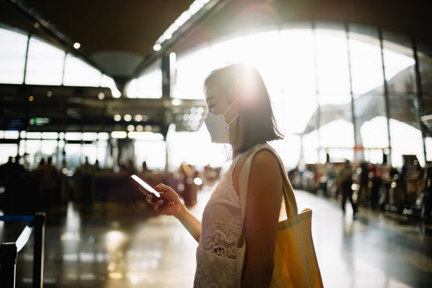 Image of an Asian Chinese woman using with protective face mask using smartphone at airport terminal