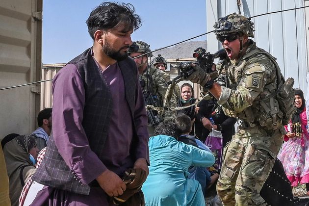 A US soldier point his gun towards an Afghan passenger at the Kabul airport. 