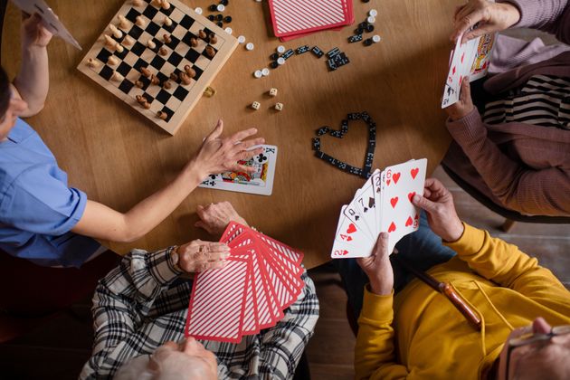 Cheerful group of seniors playing board games at nursing home.