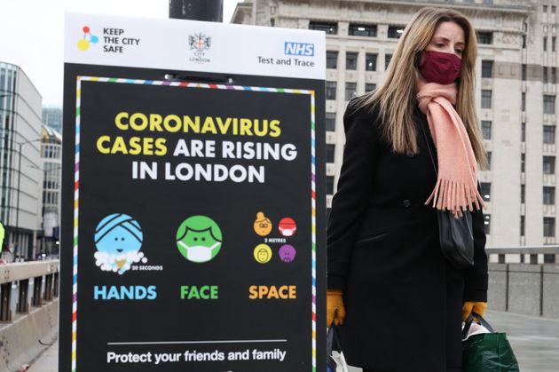 <strong>A woman walking past a coronavirus information sign on London Bridge.</strong>