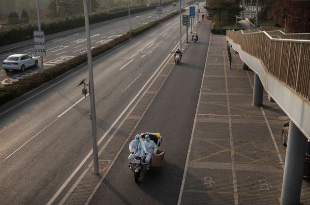 Epidemic control workers wear protective clothing to guard against the spread of COVID-19 as they drive on a nearly empty street with equipment in the Central Business District of Beijing on Nov. 23.