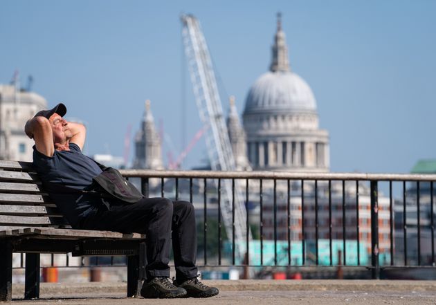 A man soaks up the sun within sight of St Paul's Cathedral on the South Bank, London. 