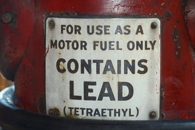 A sign on a vintage gasoline pump advises that the gas contains lead (tetraethyl). 