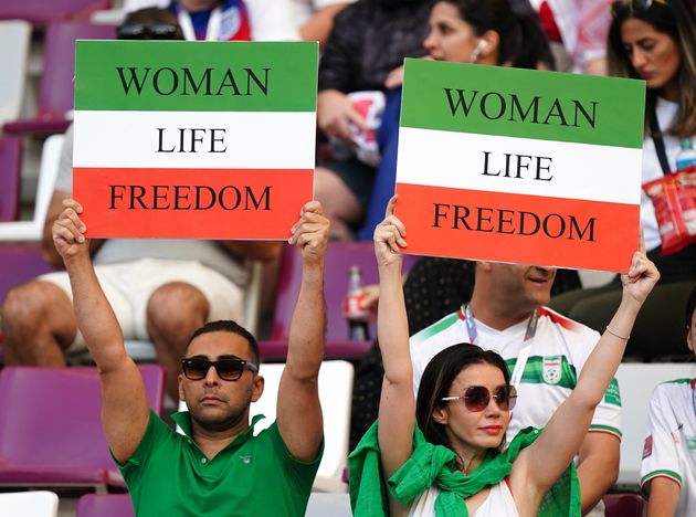 Iran fans in the stands hold up signs reading 