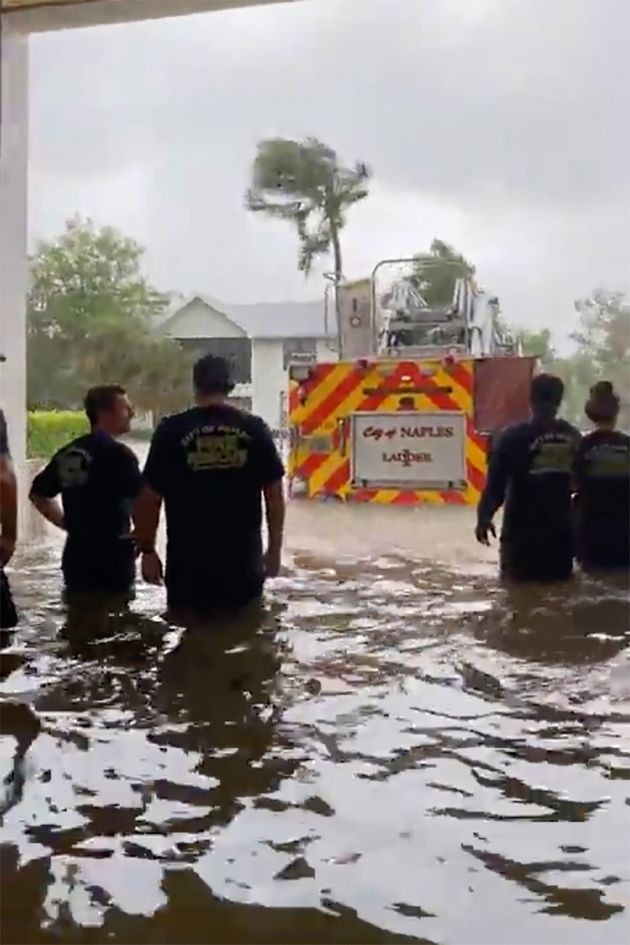 Firefighters look out at a firetruck that stands in water amid the storm surge from Hurricane Ian on Wednesday in Naples.