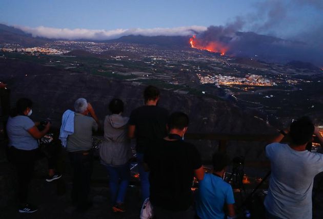 People watch lava flowing after the eruption of a volcano on the Canary Island of La Palma, as seen from Tijarafe, Spain