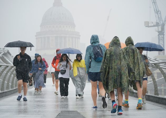 People walking along the Millennium Bridge, London, during a rain shower.